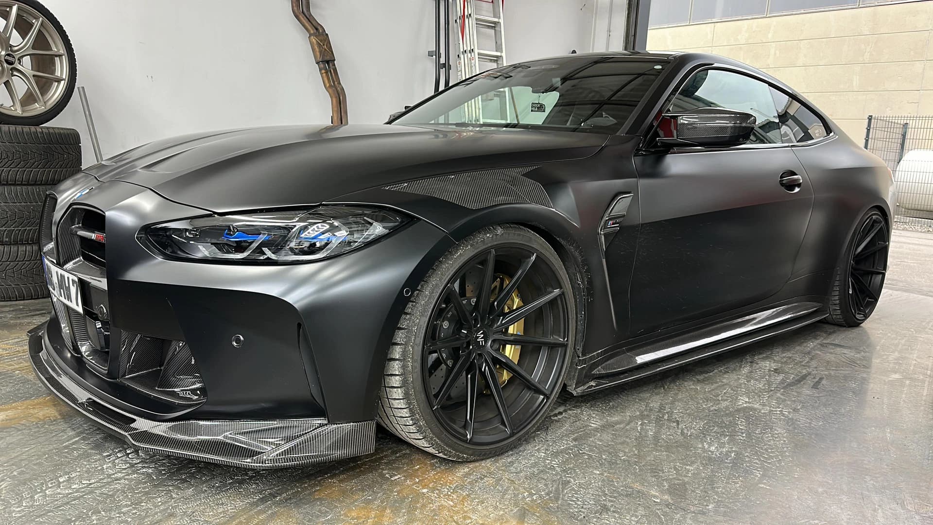 Mattschwarzer BMW M4 mit Carbon-Anbauteilen und goldenen Bremssätteln