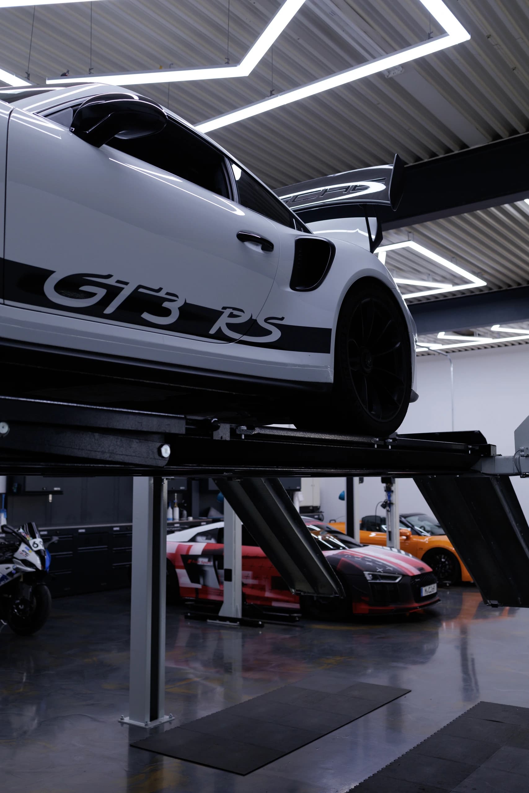 Weißer Porsche 911 GT3 RS auf der Motorsport-Hebebühne über zwei Audi R8