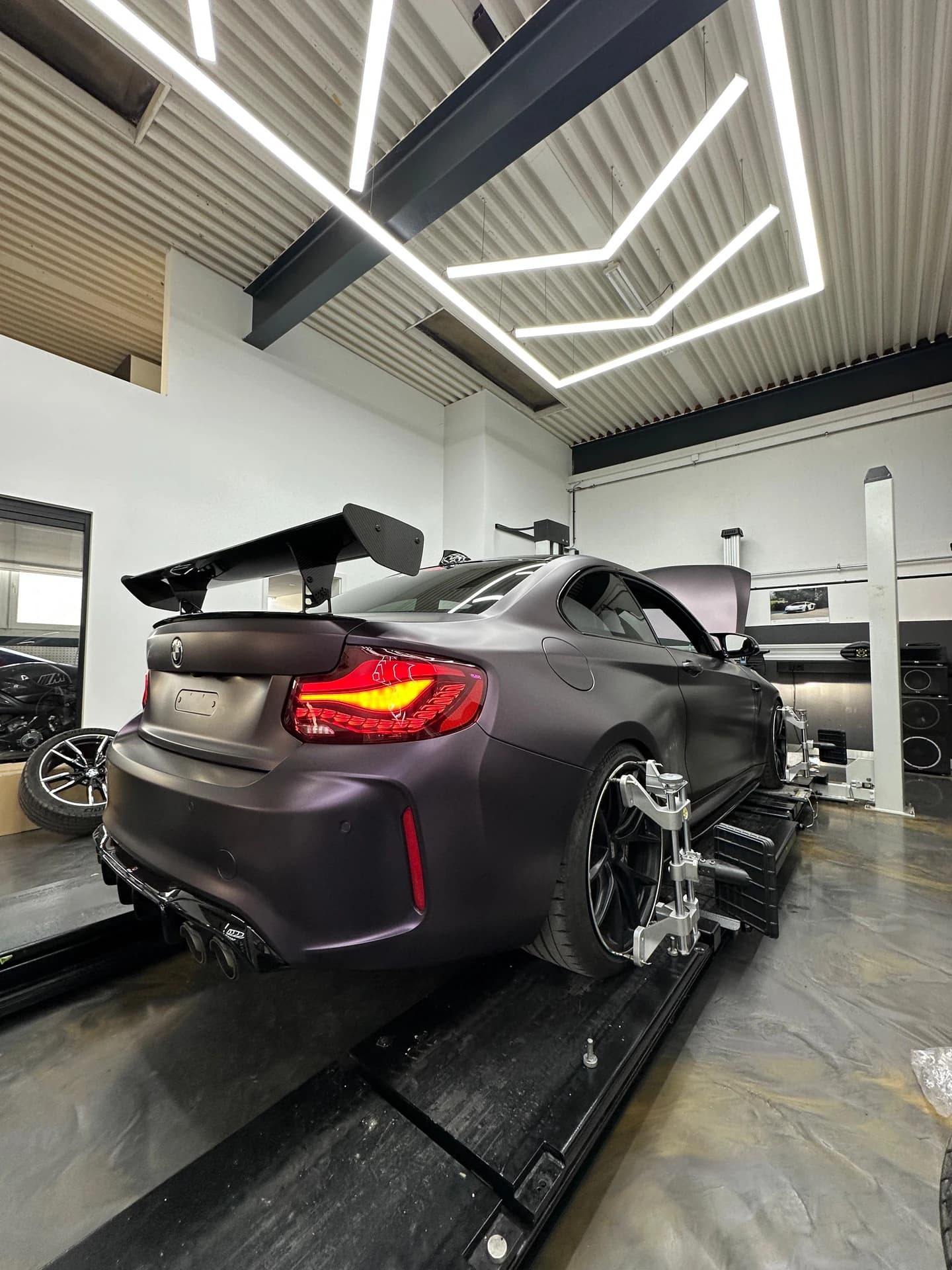 Matt violetter BMW M2 mit GT-Heckflügel auf der Achsvermessung